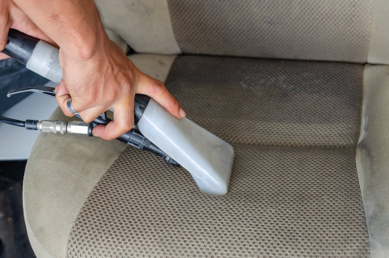 Crafting Captivating Headlines: Your awesome post title goes here Hands using a vacuum nozzle to deeply clean a fabric car seat, removing dirt and stains.